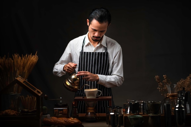 Foto barista macho vierte agua hirviendo en el vaso de café, haciendo una taza de filtro de goteo de café