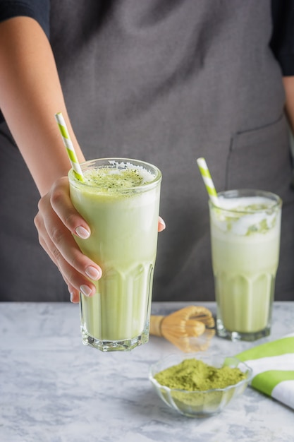 Barista Mädchen serviert ein Glas Matcha grünen Tee.