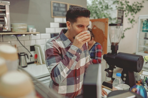 Barista-Mann im karierten Hemd probiert Kaffee