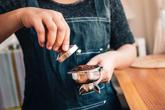 barista de mano o cafetera sosteniendo un portafiltro y un tamper de café haciendo un café espresso