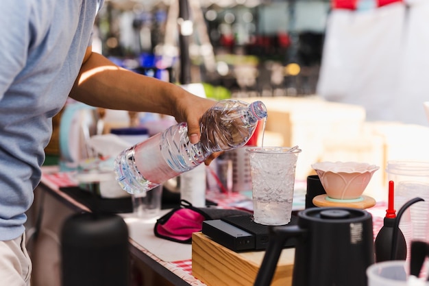 Barista mano vertiendo agua en vaso de plástico con helado