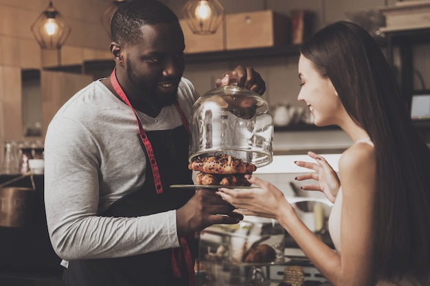 Barista masculino ajuda uma menina a escolher uma sobremesa