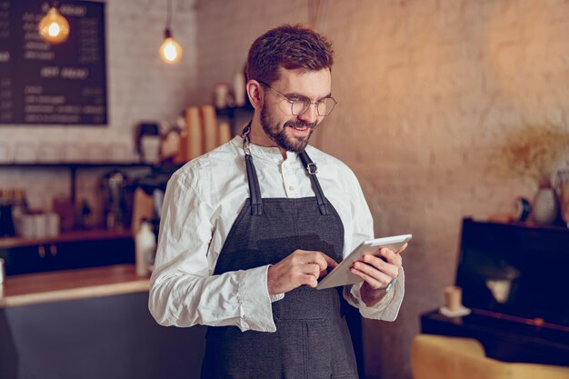 Barista masculino alegre usando computador tablet no café