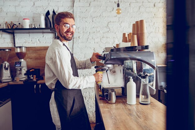 Barista masculino alegre usando máquina de café no café