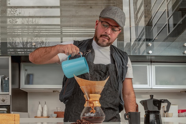 Barista masculino está fazendo café preto na cafeteira chemex, em frente ao bar da cafeteria