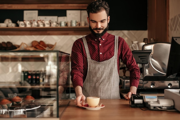 Barista masculino poniendo café en el mostrador