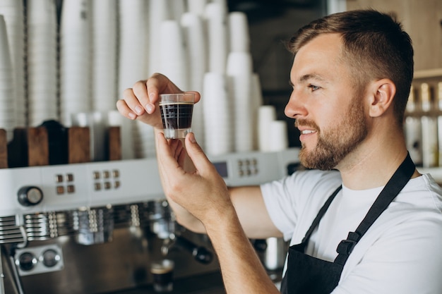 Barista masculino preparando café en una cafetería.