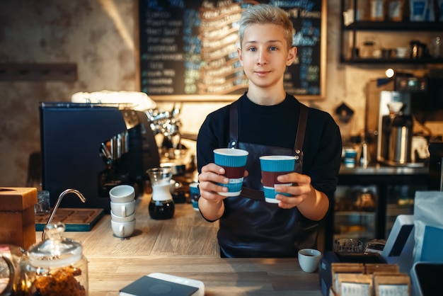 Barista masculino tiene dos tazas de café caliente recién hecho