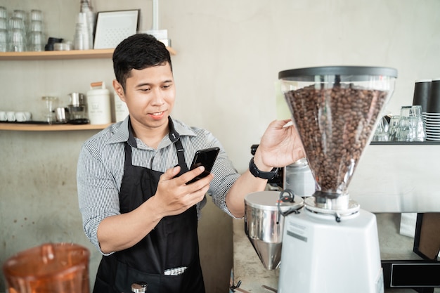 Barista masculino usando smartphone