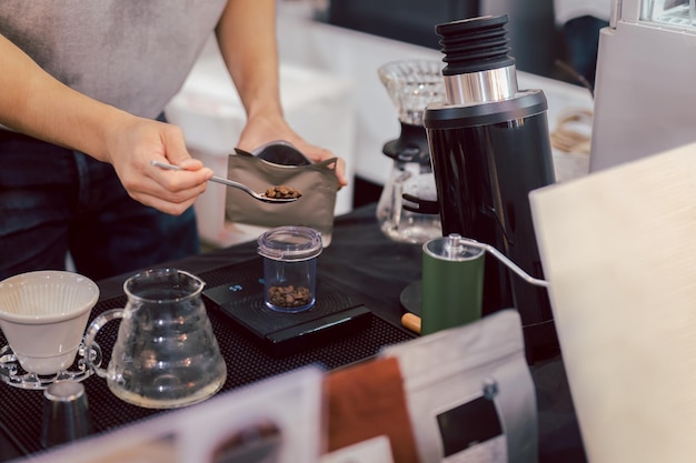 Barista medindo grãos de café torrados em escala antes de preparar café