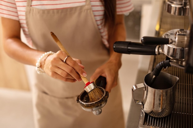 Barista mit Spezialbürste beim Reinigen von Teilen der Kaffeemaschine