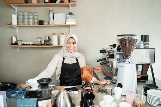 Barista mujer sonriendo cuando se paran en la cafetería pub