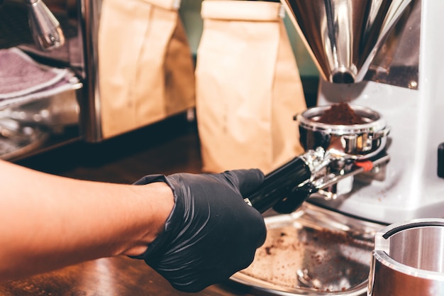 Barista de mujeres usando una máquina de café para hacer café en la cafetería