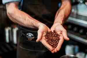 Foto barista ofreciendo frijoles asados en manos en tazas