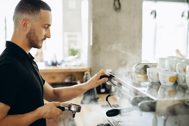 Barista preparando café en la máquina de café y sosteniendo portafiltro