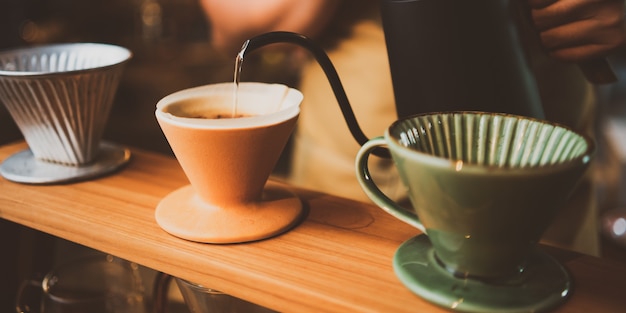 Barista preparando un goteo de filtro de café por la mañana, bebida con aroma fresco de espresso negro, bebida caliente en una taza de cafés, cafeína marrón en el fondo de la tienda del bar