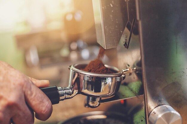 Barista preparando portafiltros con harina de café en molinillo de café.