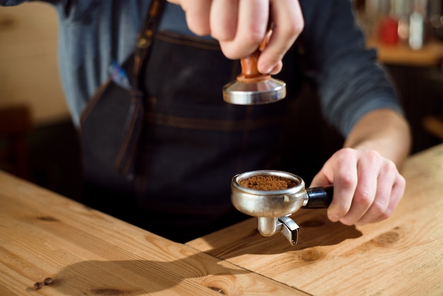 Barista presiona el café molido usando manipulación en una cafetería