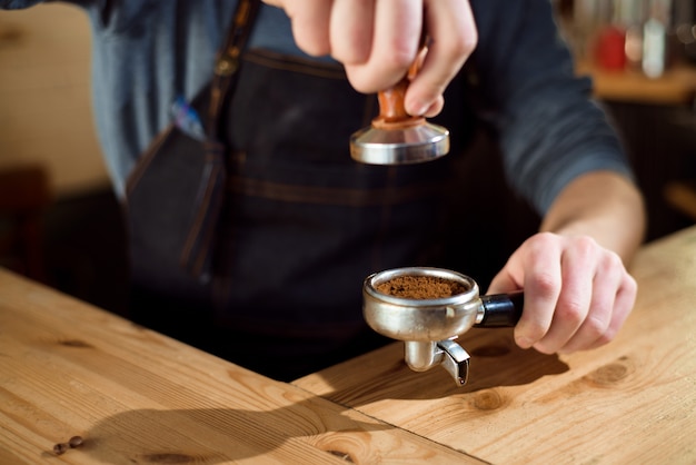 Barista pressiona café moído usando tamper em uma cafeteria