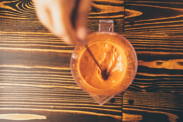 Barista profesional hace una bebida fresca con té y leche en la taza, bebida sabrosa en la cafetería del bar, mano que sostiene el café con leche en la cafetería o restaurante de comida, camarero que trabaja en el uniforme de la cafetería