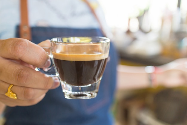 Barista profesional que sostiene una taza de café caliente en café.