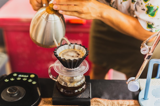 Foto barista profissional preparando café usando chemex derramando sobre a cafeteira e a chaleira de gotejamento