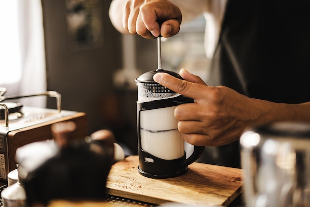 Barista pumpen und schütteln Milch für schaumigen Latte-Kaffee