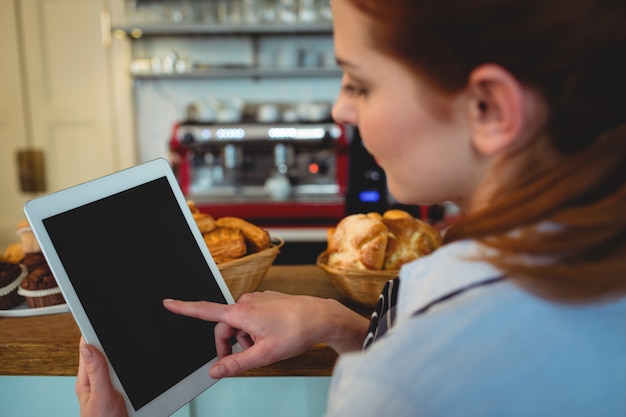 Foto barista rolagem tablet digital no café