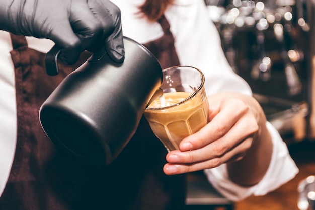 Barista segurando o leite para fazer café latte art em coffee shop