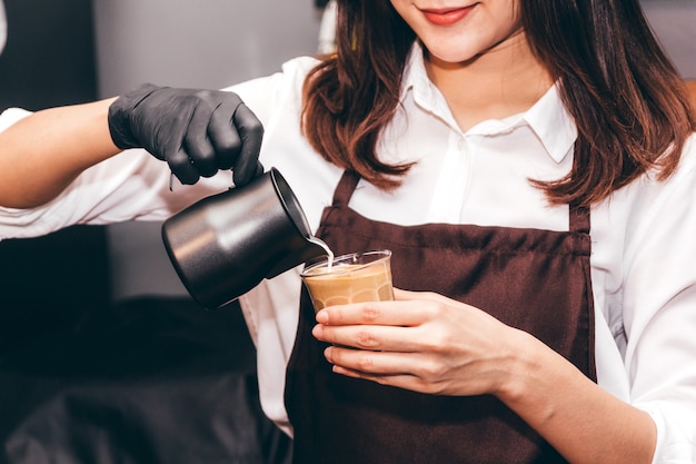 Barista segurando o leite para fazer café latte art em coffee shop