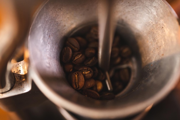 Barista segurando o moedor de mão para fazer bebidas moendo grãos de café torrados para bebida de cafeína no fundo do café da cozinha preparação do moinho de café da manhã com equipamento de café expresso em tom marrom