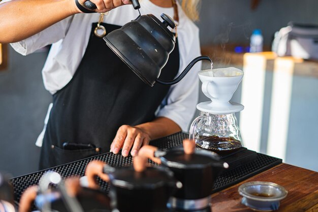 Barista sirviendo café de la cafetera de moca a una taza de café Mano sosteniendo la clásica moca italiana sirviendo café