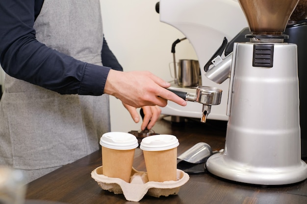 Barista sirviendo café en tazas para llevar en la cafetería en máscara