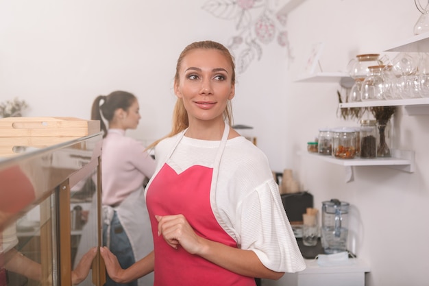 Barista sonriendo con alegría, trabajando en su cafetería.