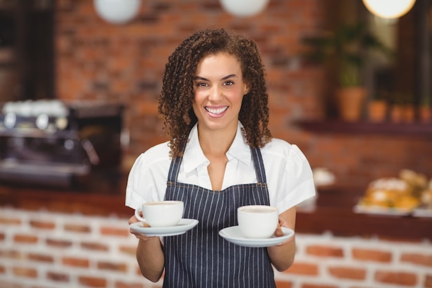 Barista sorridente que serve duas xícaras de café