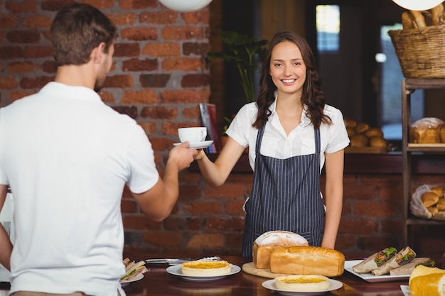 Barista sorridente que serve um cliente