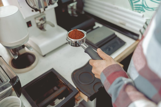 Barista steht in der Nähe des Arbeitsplatzes und hält Filter in den Händen