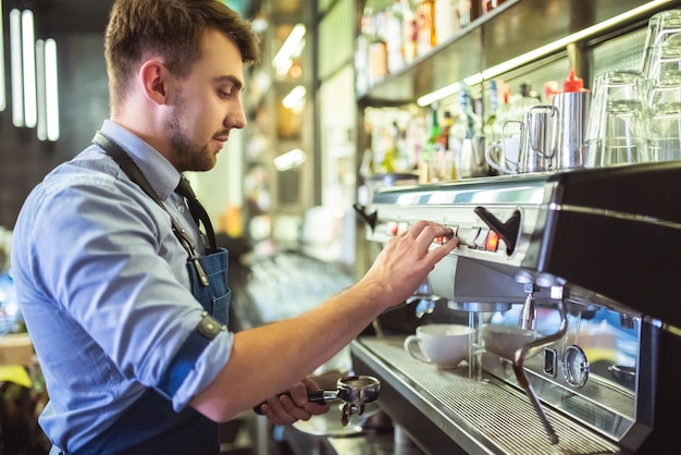 El barista trabajando con una máquina de café en la barra.