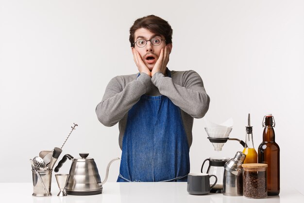 Barista, trabalhador de café e barman conceito. Chocado sem fala jovem caucasiano de avental, olhando chocado olhar como o cliente bebe seu café errado, em pé perto do balcão de bar com chemex