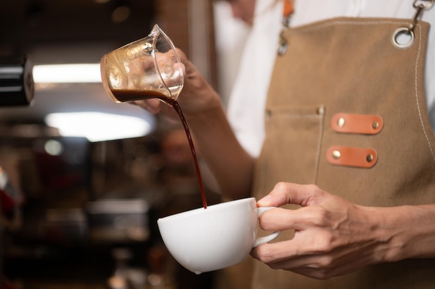 Foto barista vertiendo café en una taza en una cafetería de primer plano