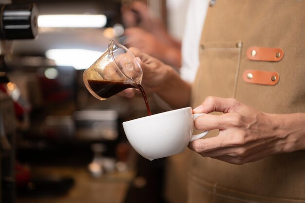 Barista vertiendo café en una taza en una cafetería de primer plano