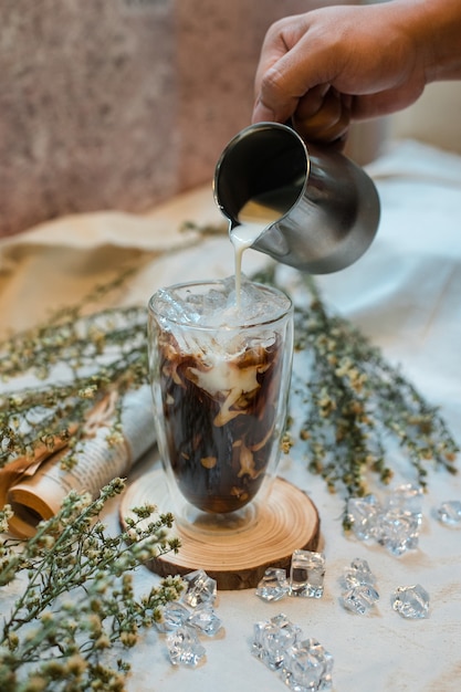 Barista vertiendo leche en un vaso de café helado