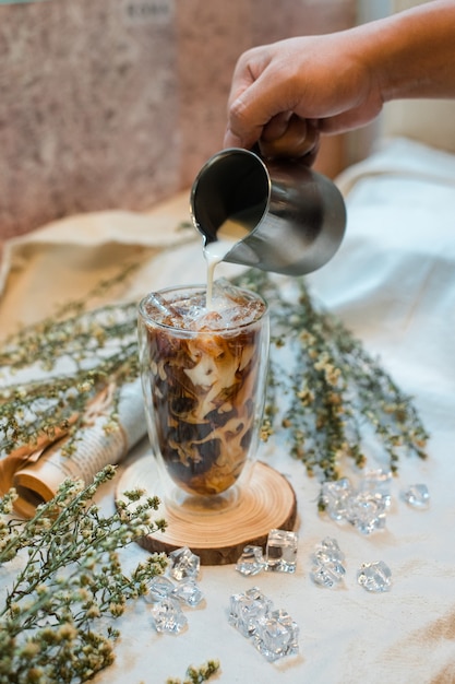 Barista vertiendo leche en un vaso de café helado