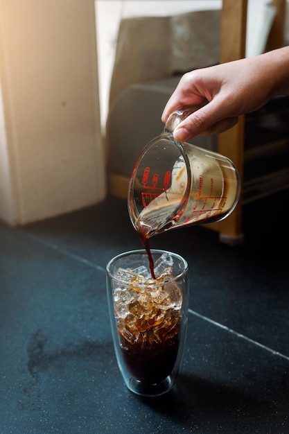 Barista vertiendo leche en un vaso de café helado