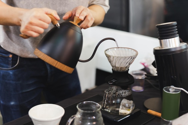 Barista vierte agua caliente en el café de burbujas marrones ásperas a través del filtro de goteo