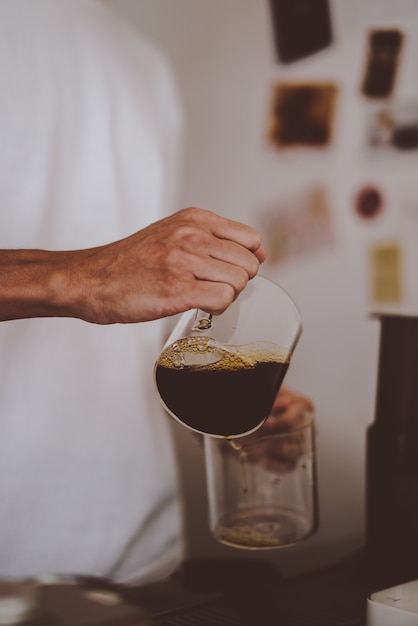 Barista vierte el café en un vaso después de preparar café, estilo de elaboración casera