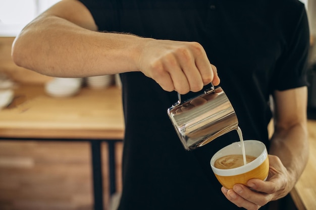 Barista vierte leche en una taza con capuchino