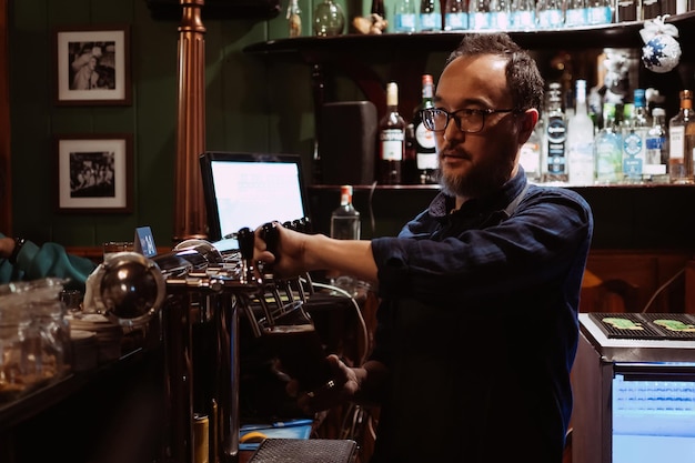 Barkeeper an der Bar gießt Bier in ein Glas mit Zapfhahn