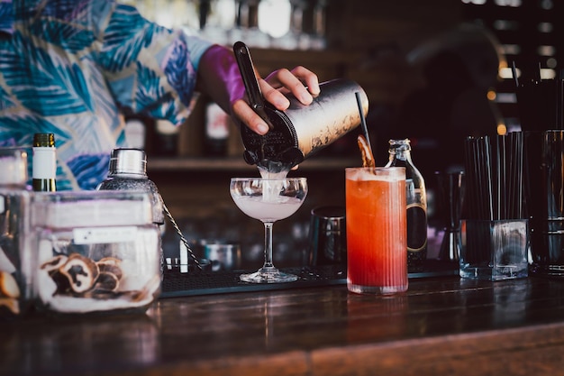 Barkeeper bereitet einen Cocktail zu, der in ein Martini-Glas gegossen wird