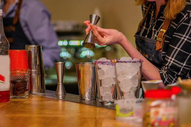 Barkeeper bereitet einen Cocktail zu. Mixologie und Bar. Nachtleben. Barkeepermädchen macht einen Cocktail